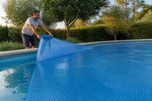 Installation d'une bâche à bulles sur une piscine, bulles orientées vers l'eau et face lisse vers le ciel
